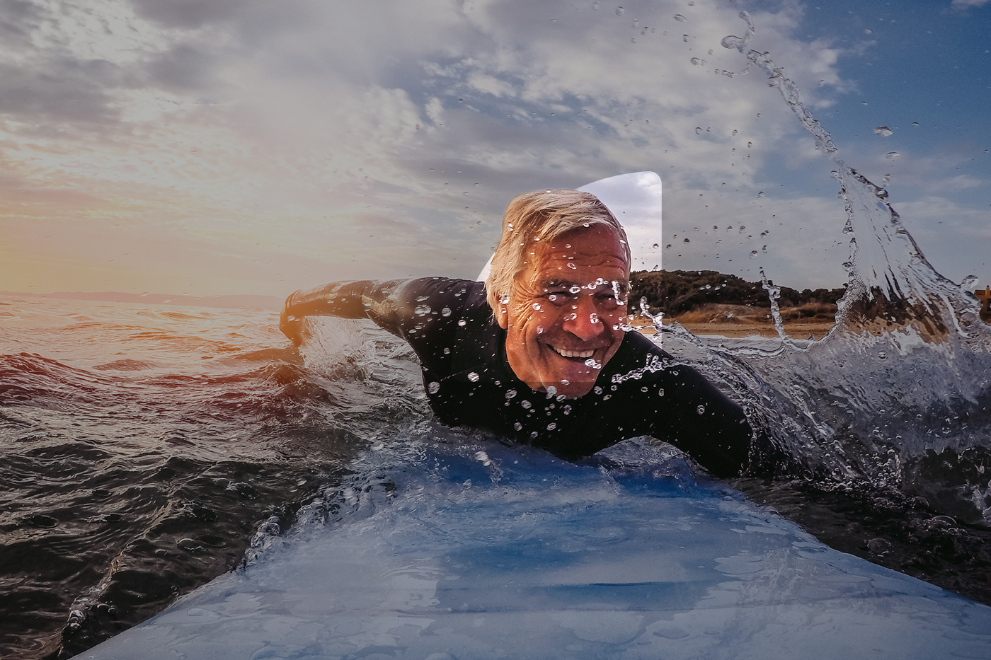 An adult man swiming on the top of his board in the sea